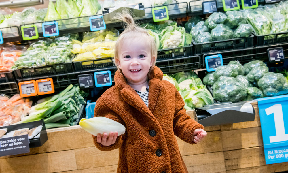 Kind met een witlof in de winkel